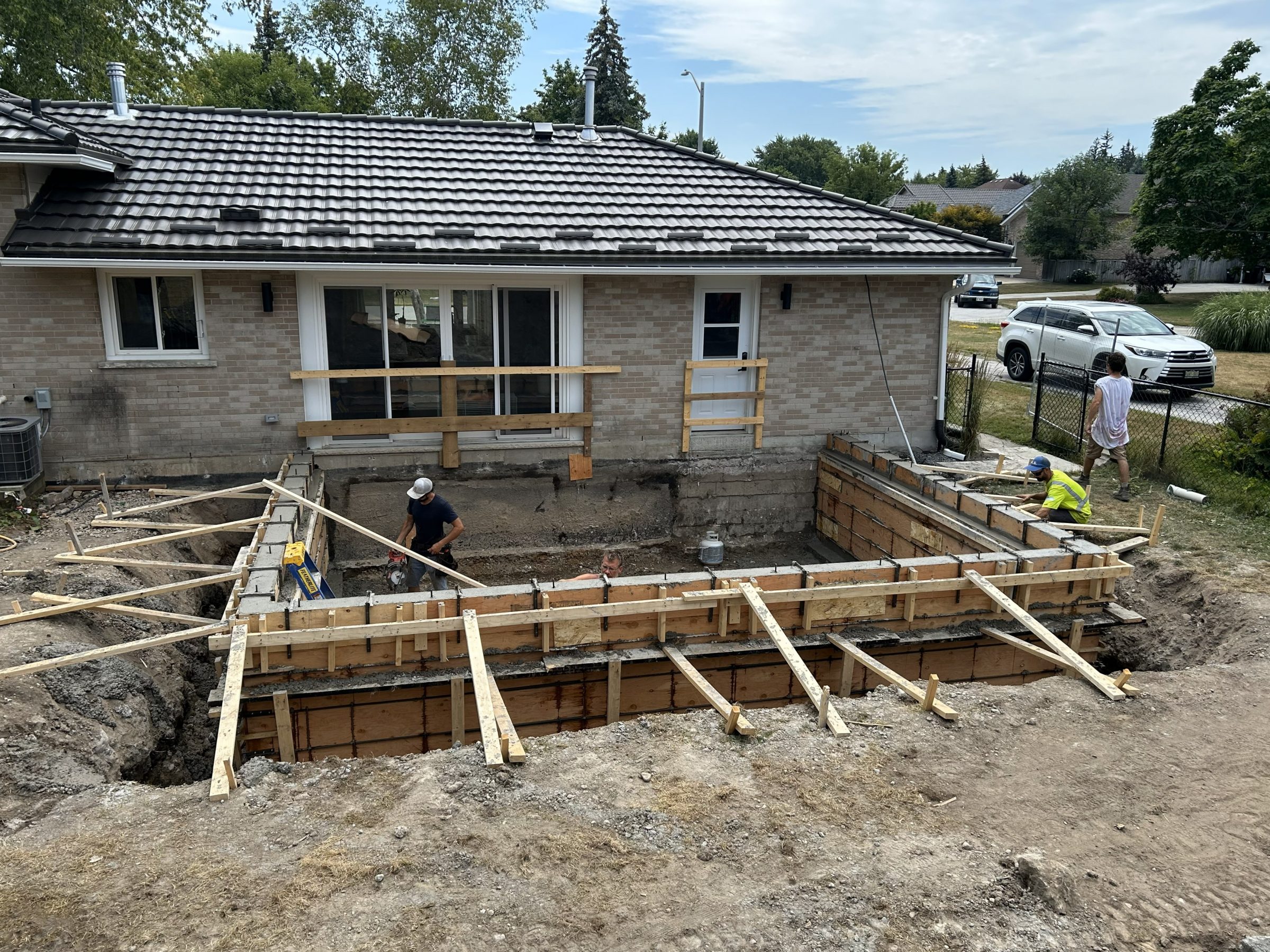 Workers building backyard home addition foundation.