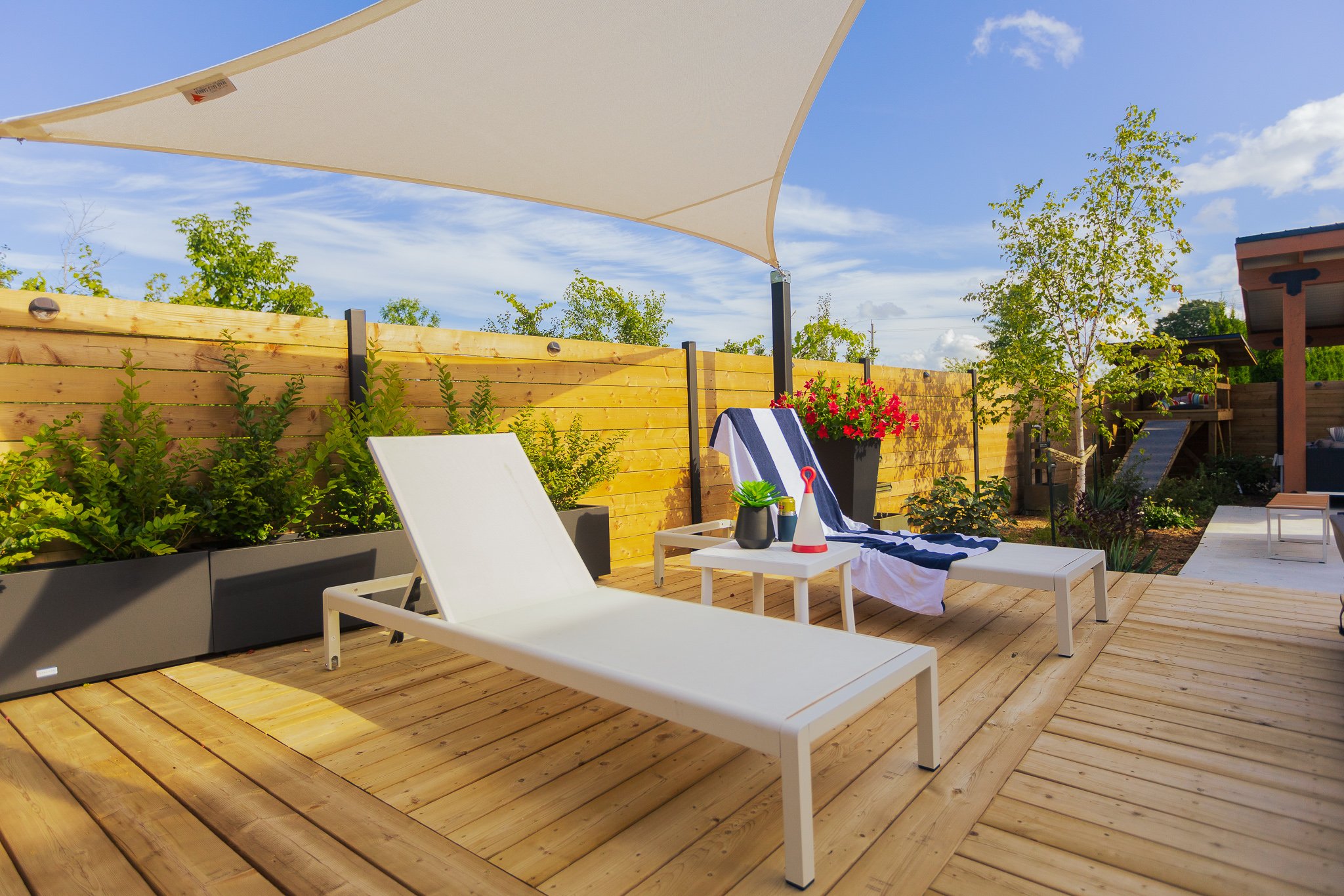 Modern backyard deck with lounge chairs and shade sail