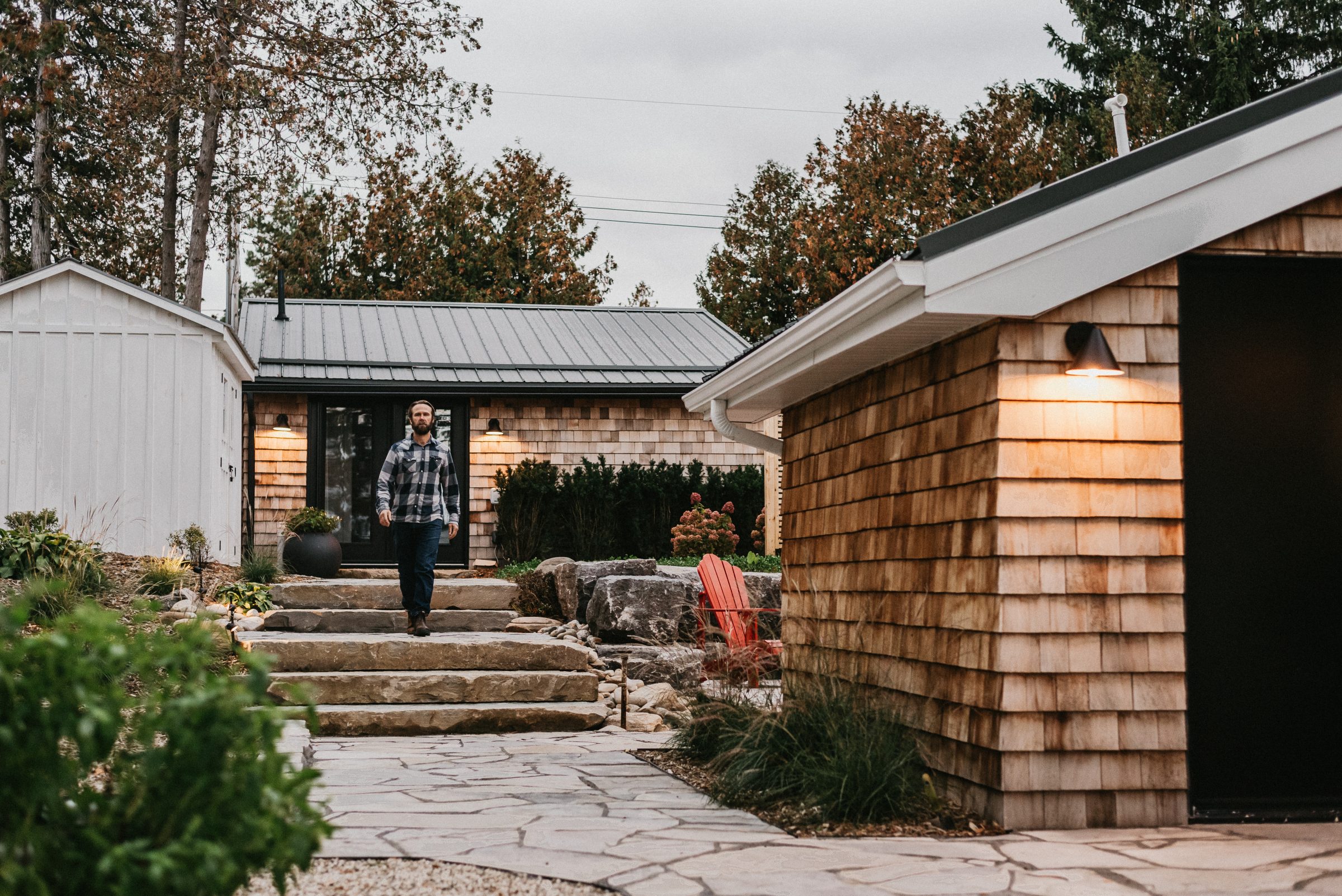 Man walking outside modern shingle-style home