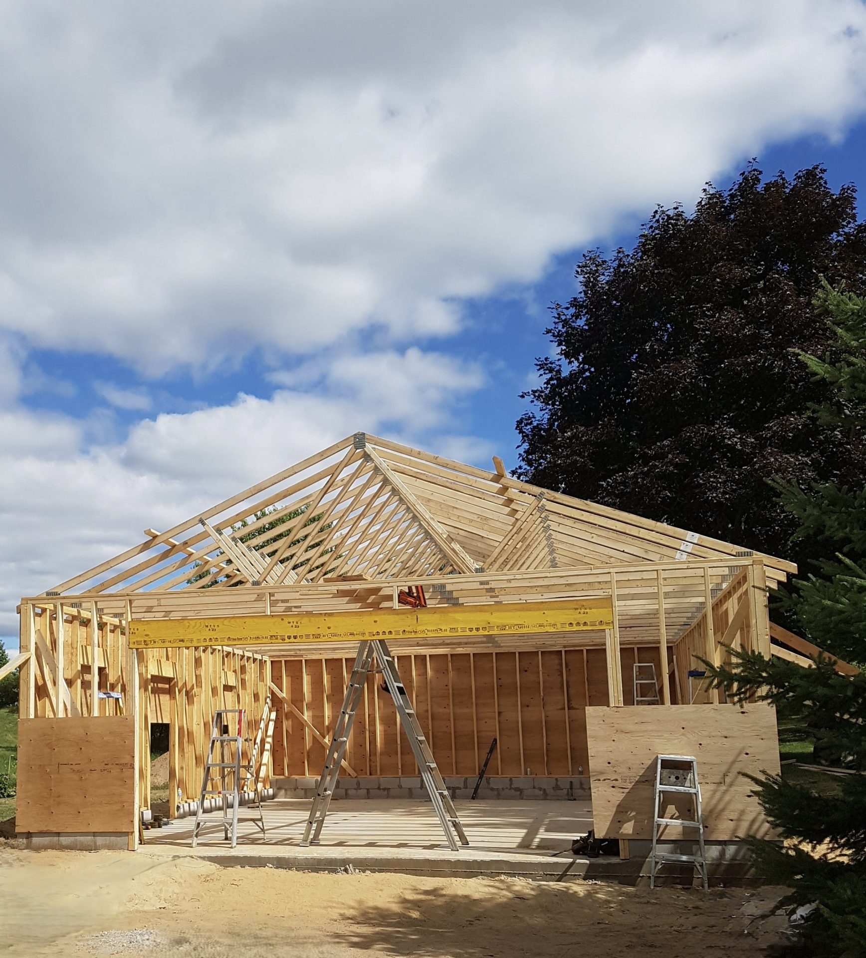 Wooden house frame under construction with roof trusses