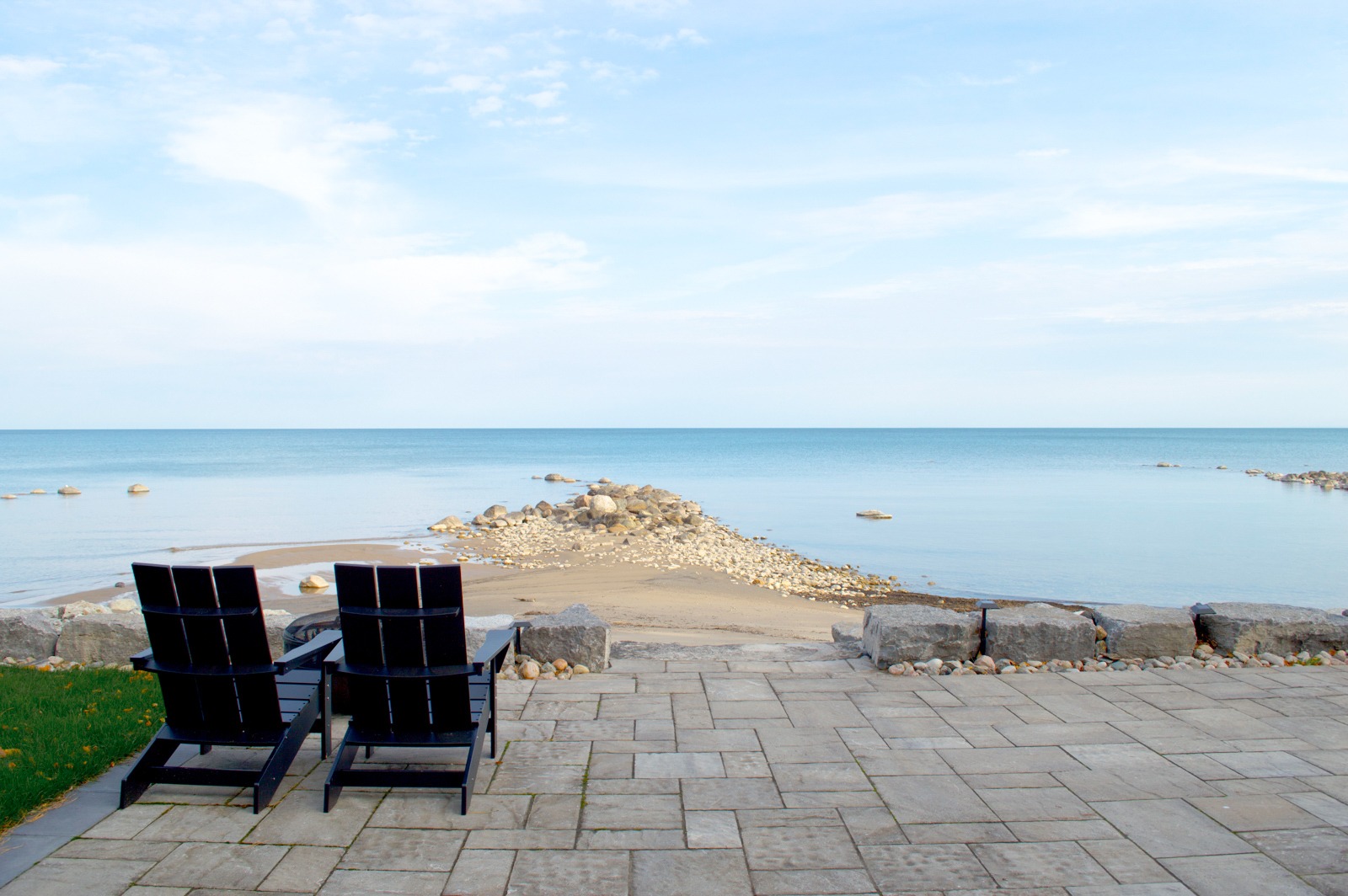 Two chairs overlooking calm lake and rocky shore