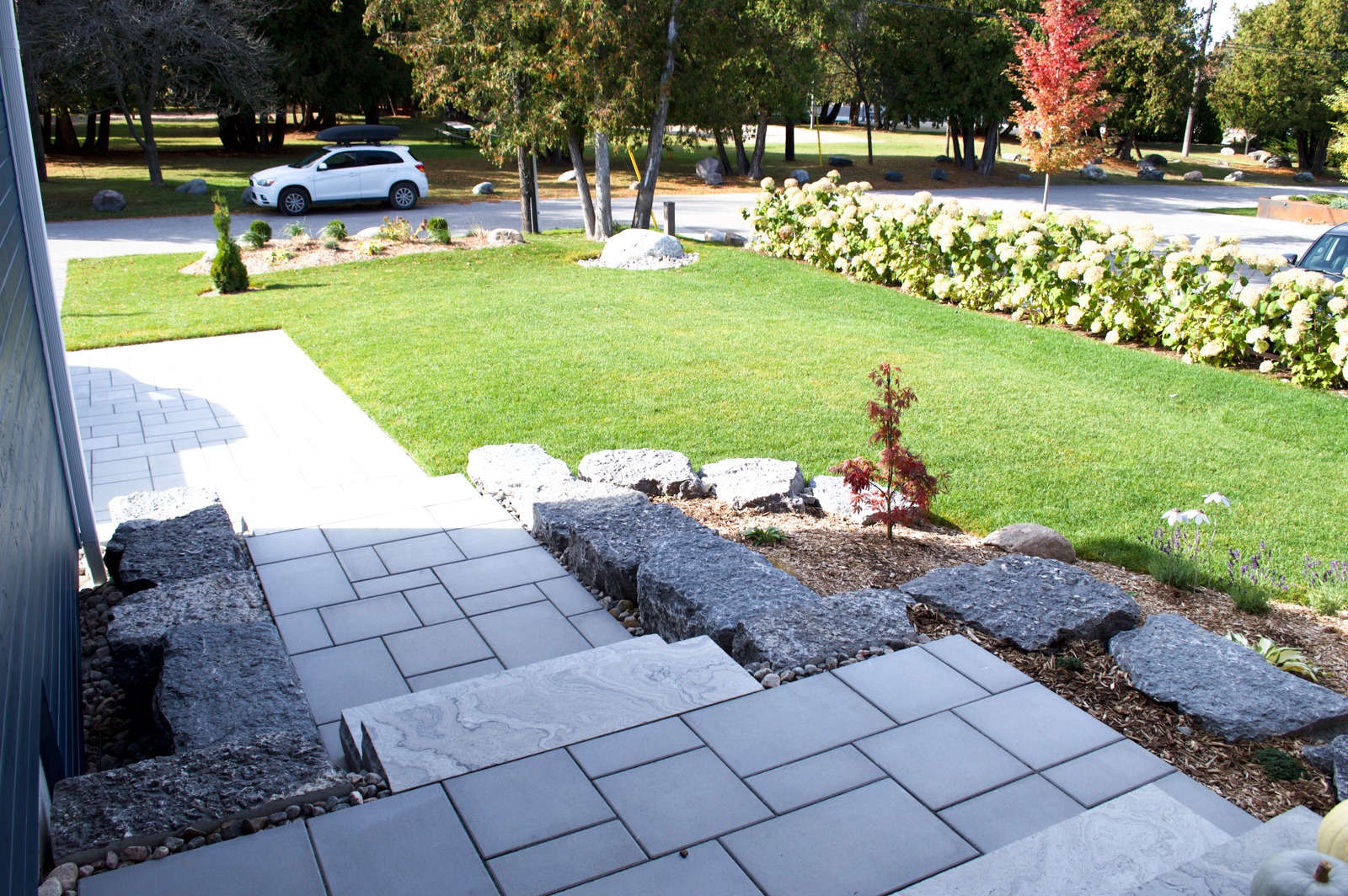 Stone steps and landscaped front yard with green lawn