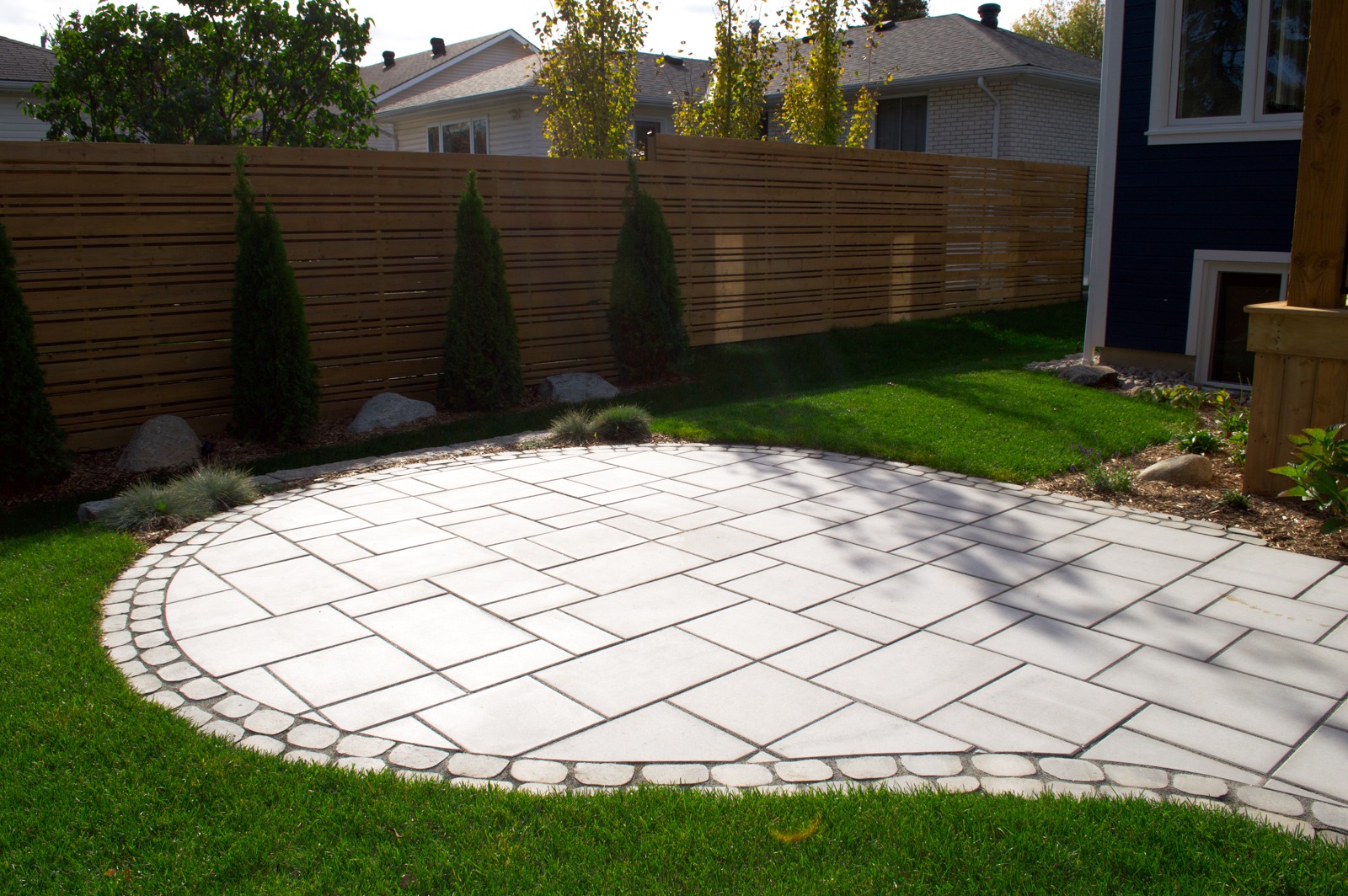 Curved stone patio in landscaped backyard