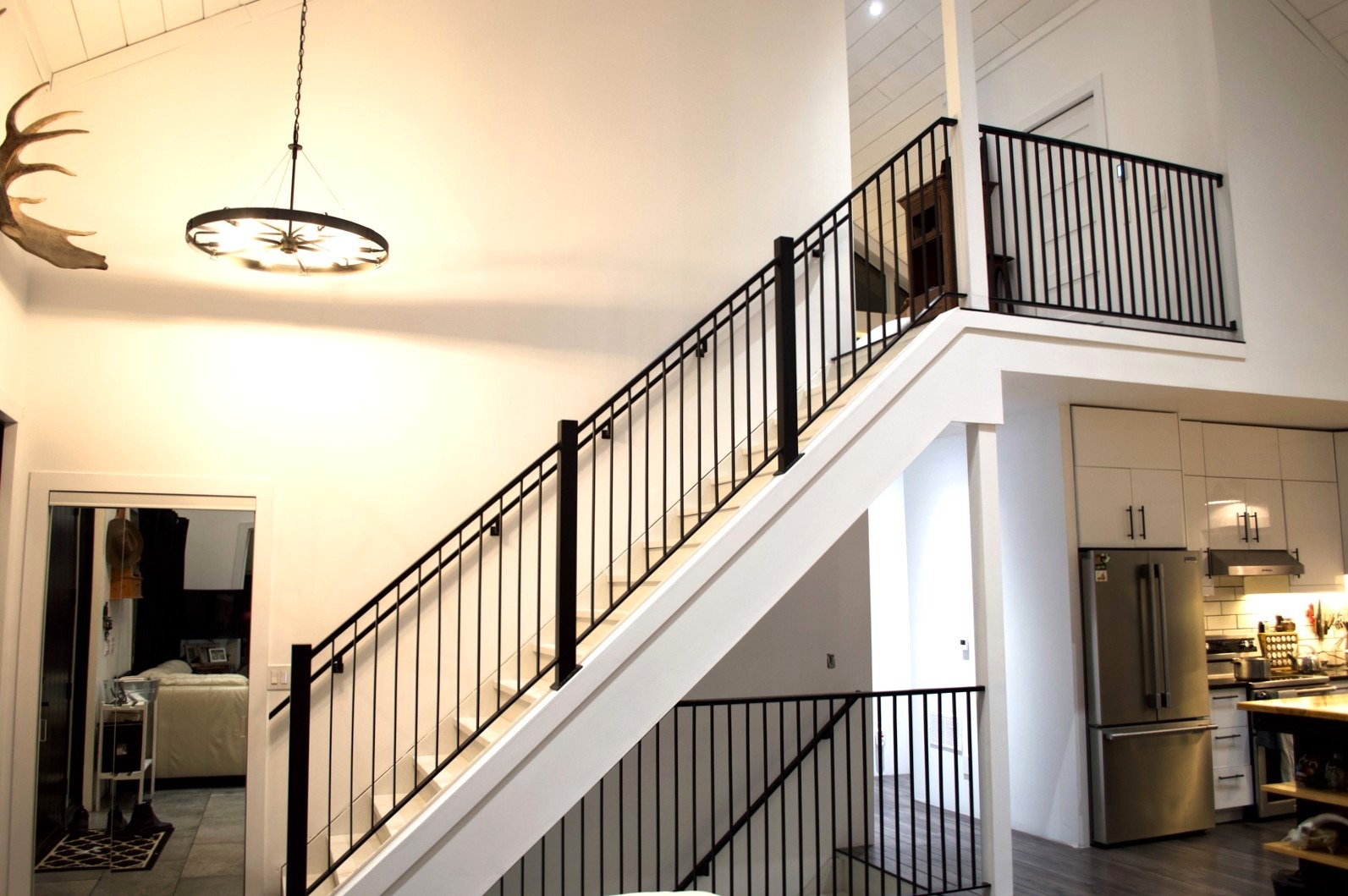 Modern staircase with black railing and loft kitchen