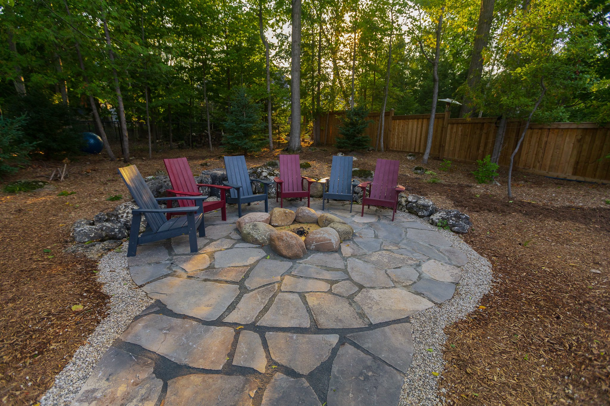 Backyard stone patio with fire pit and chairs
