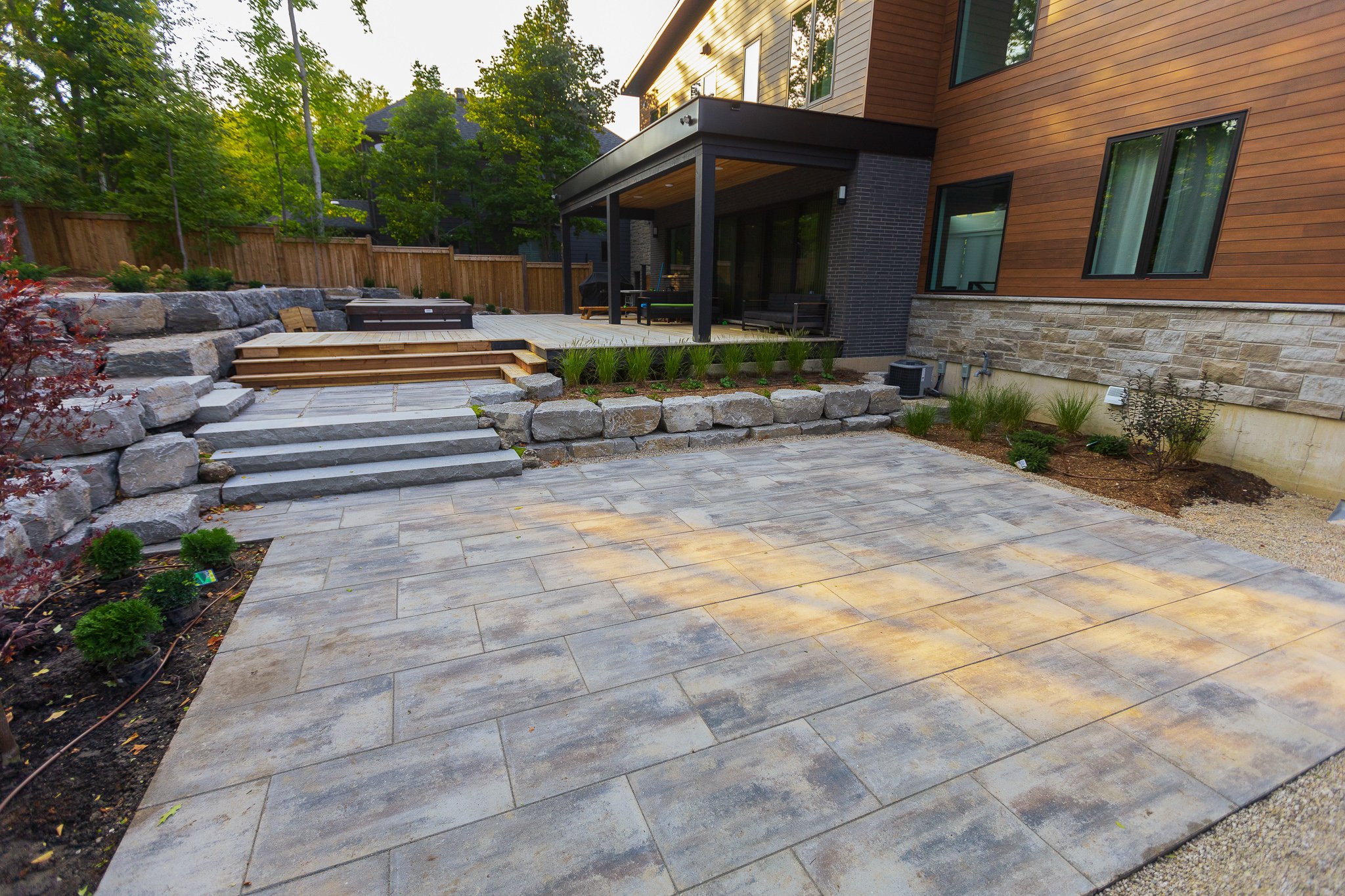 Modern backyard patio with stone pavers and deck