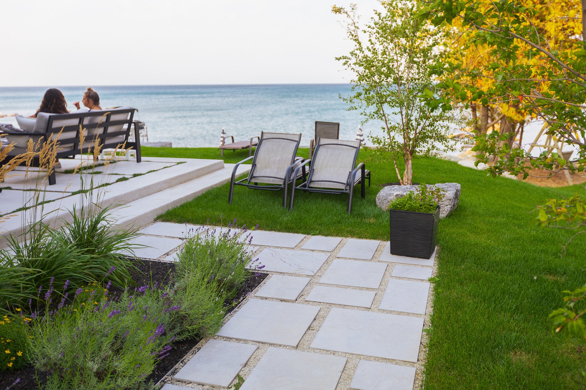Lakeside backyard patio with lounge chairs and greenery