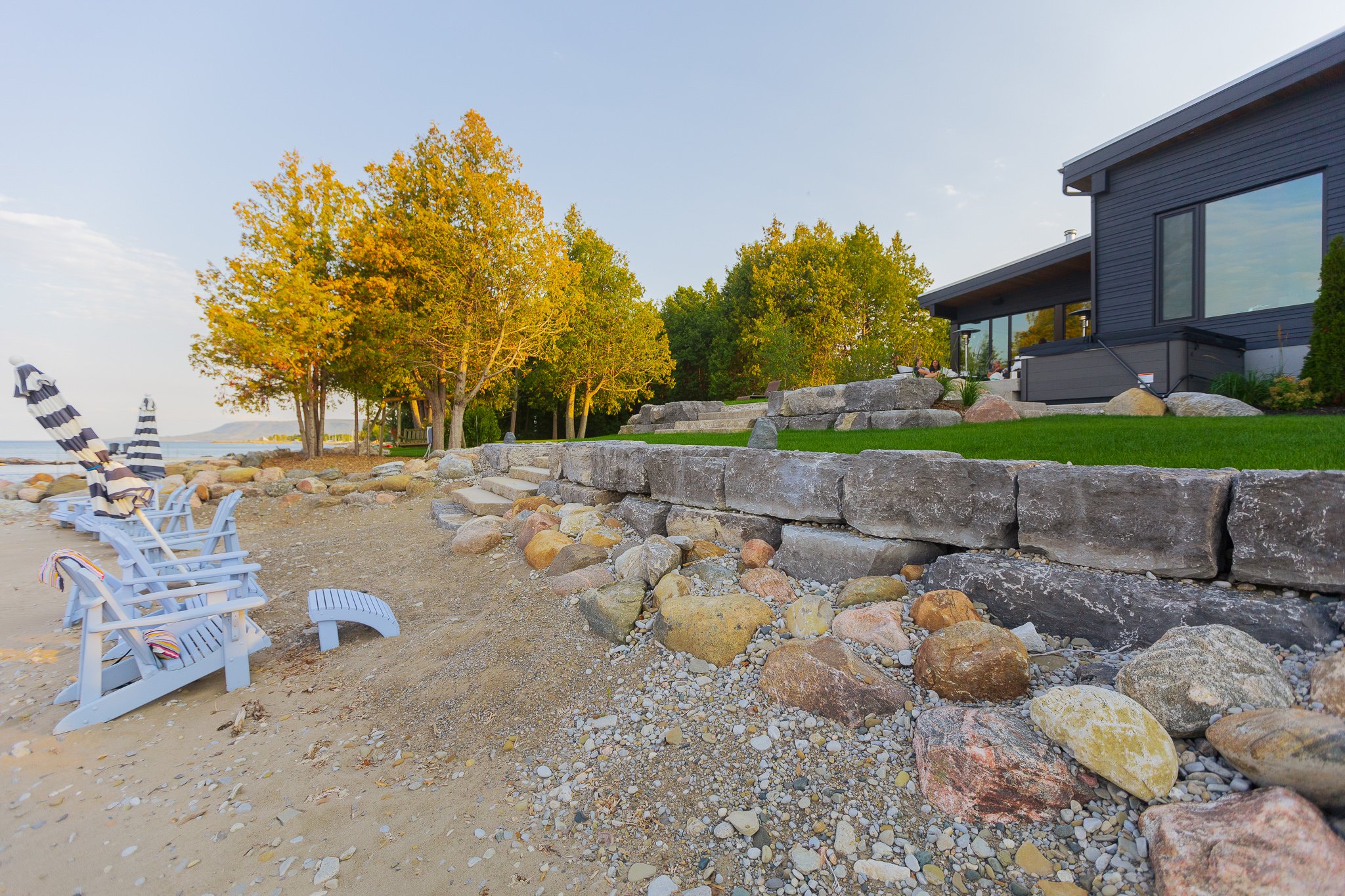 Lakeside home with beach chairs and stone wall