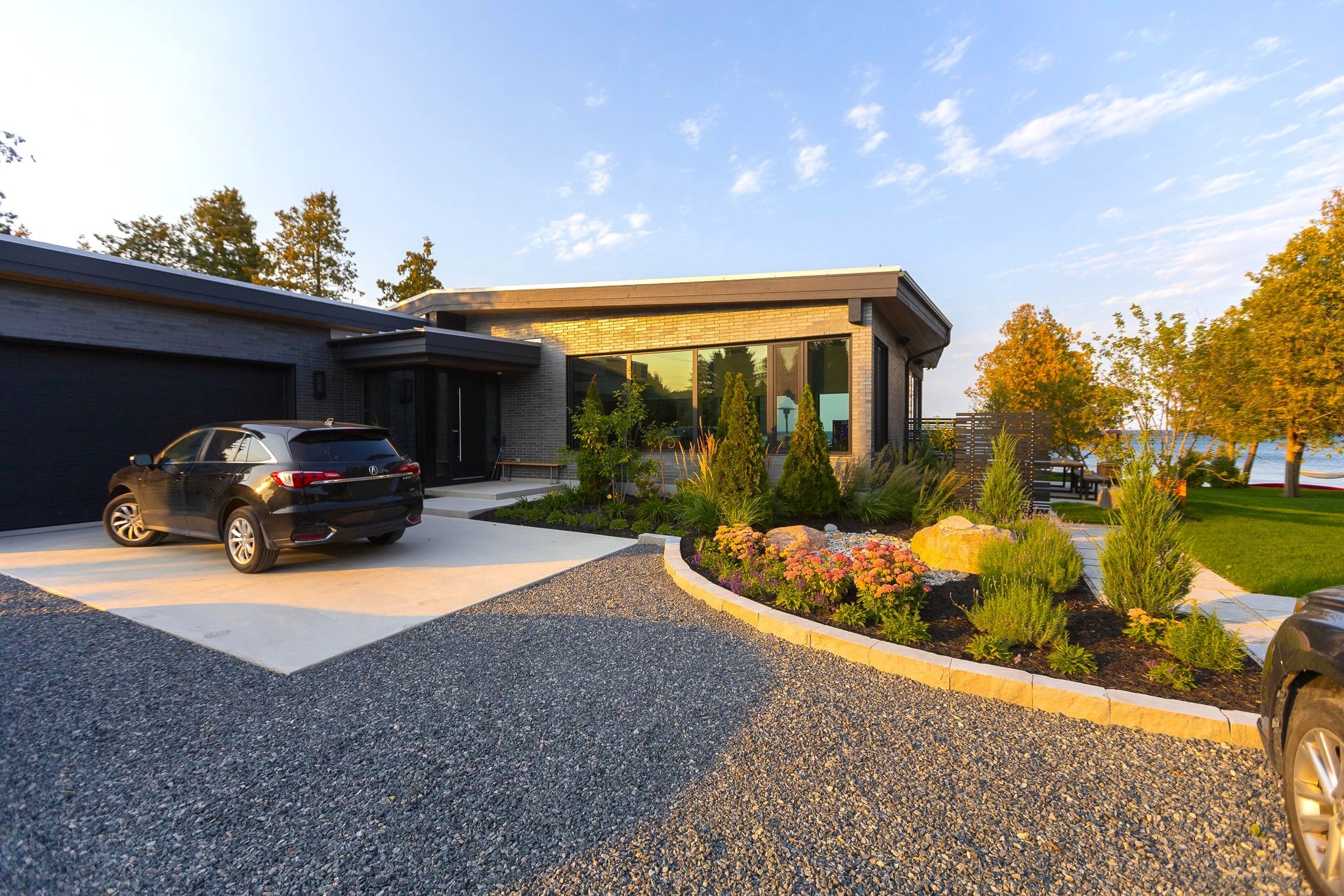 Modern waterfront home with landscaped garden and driveway