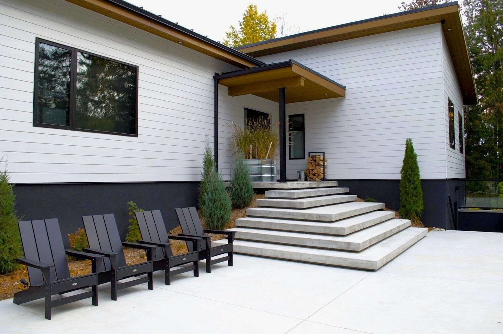 Modern home exterior with concrete steps and patio chairs