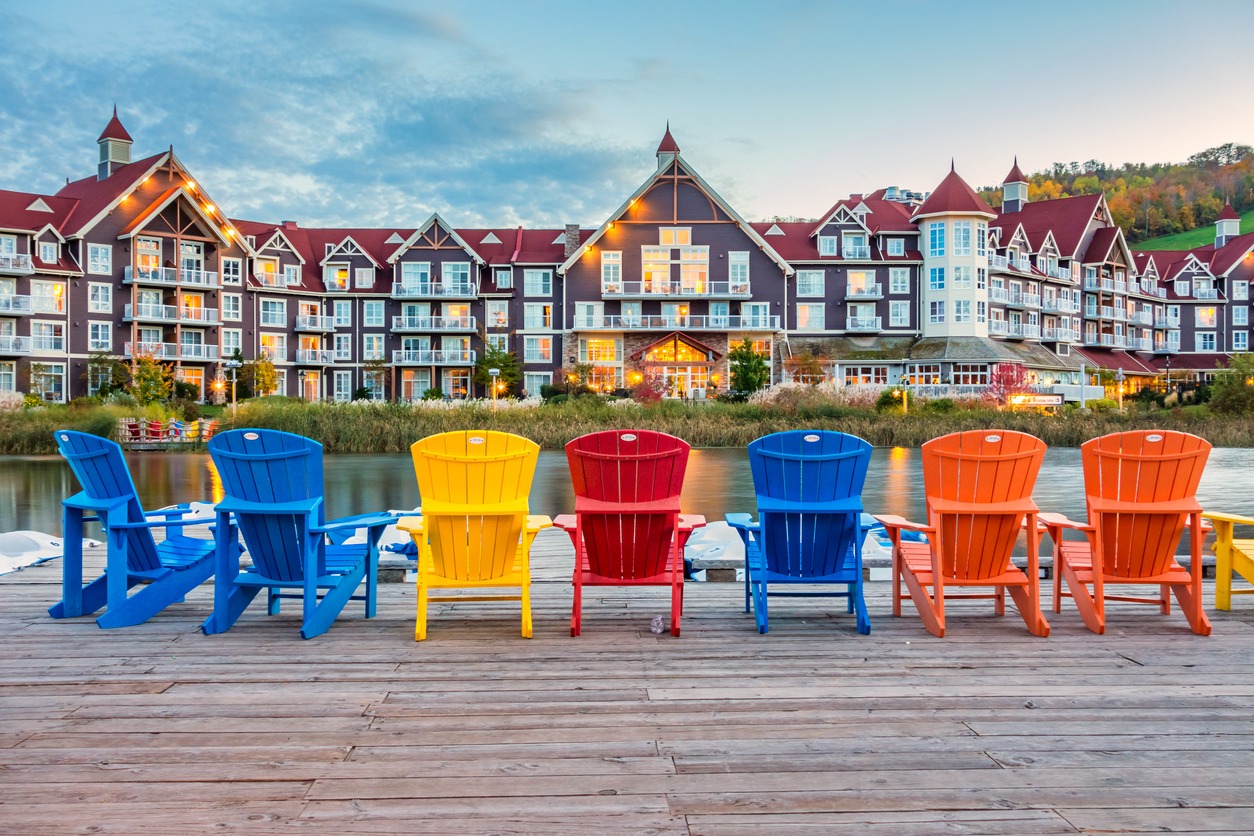 Colorful Adirondack chairs facing lakeside resort at dusk