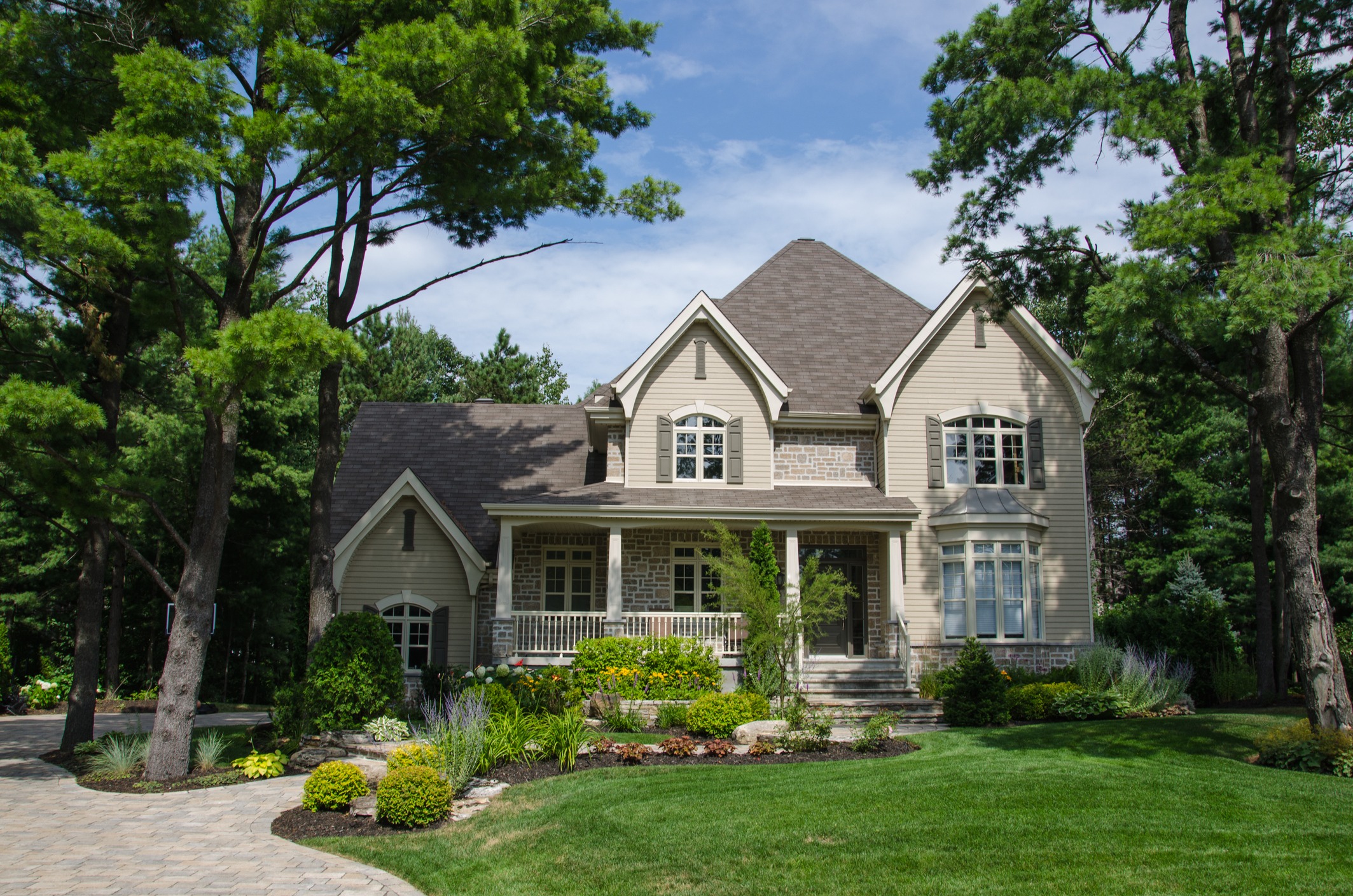 Large suburban house with landscaped lawn and trees