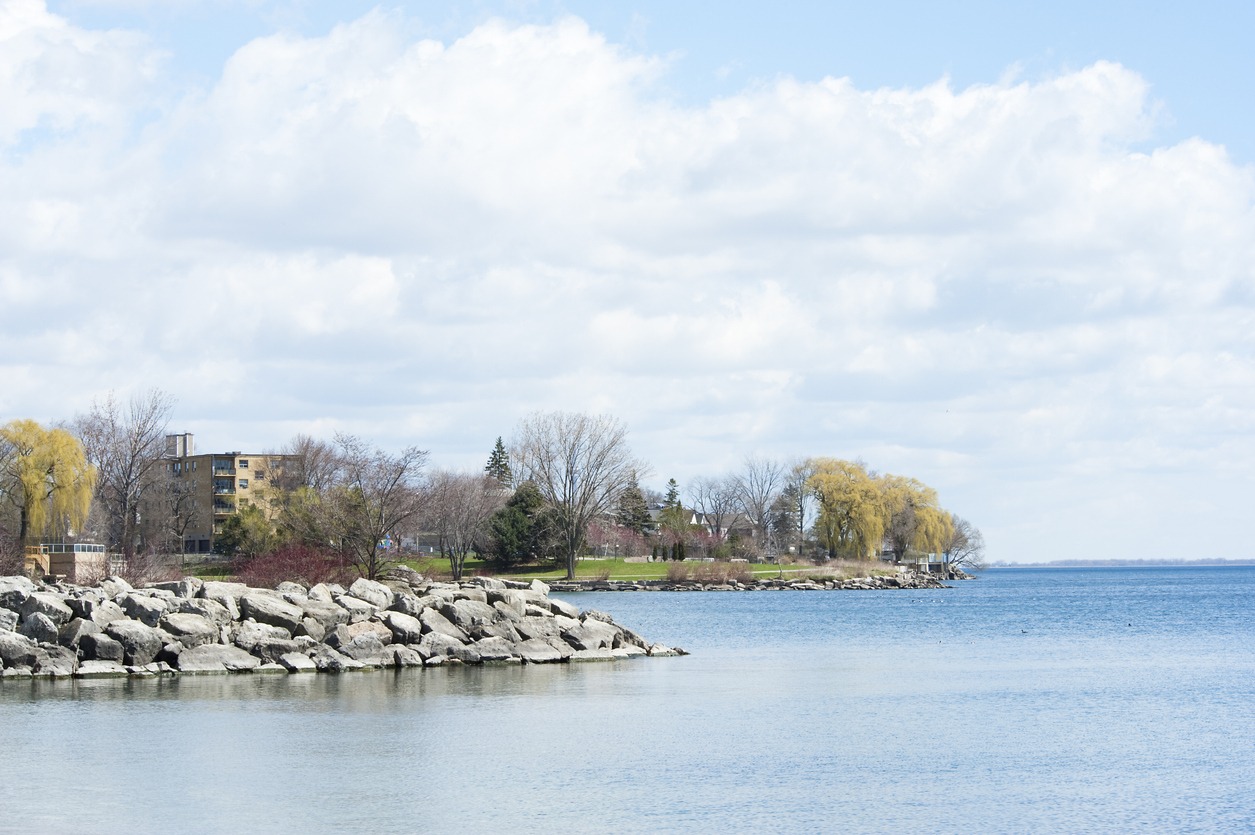 Rocky lakeshore with trees and residential buildings