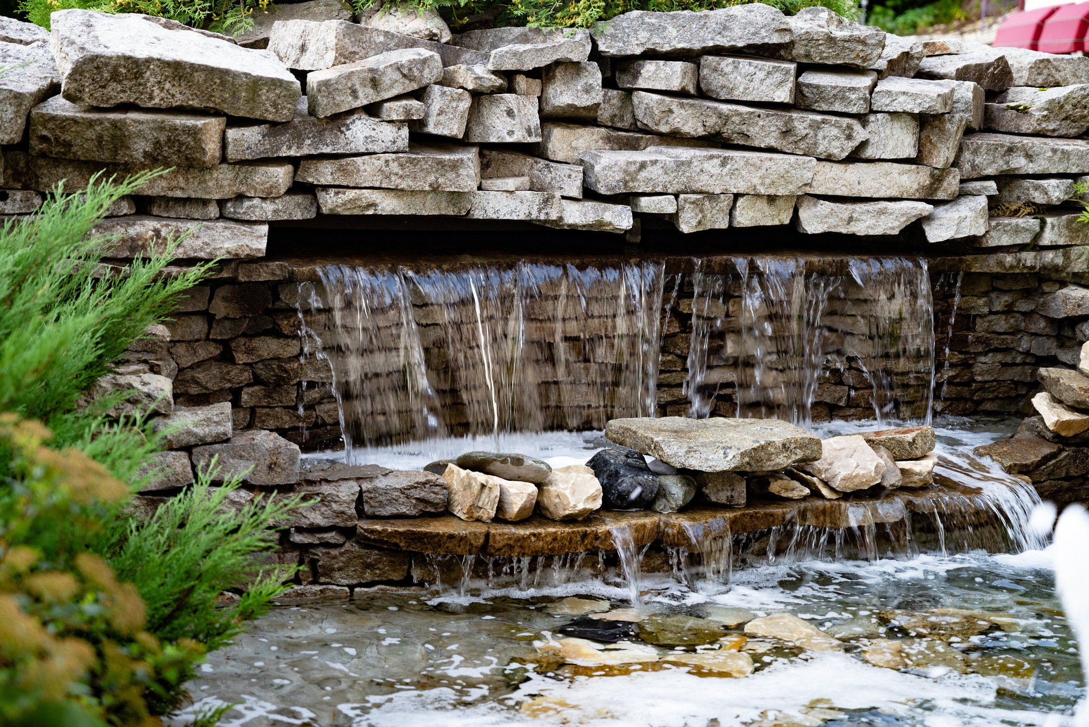 Stone waterfall feature in landscaped garden pond