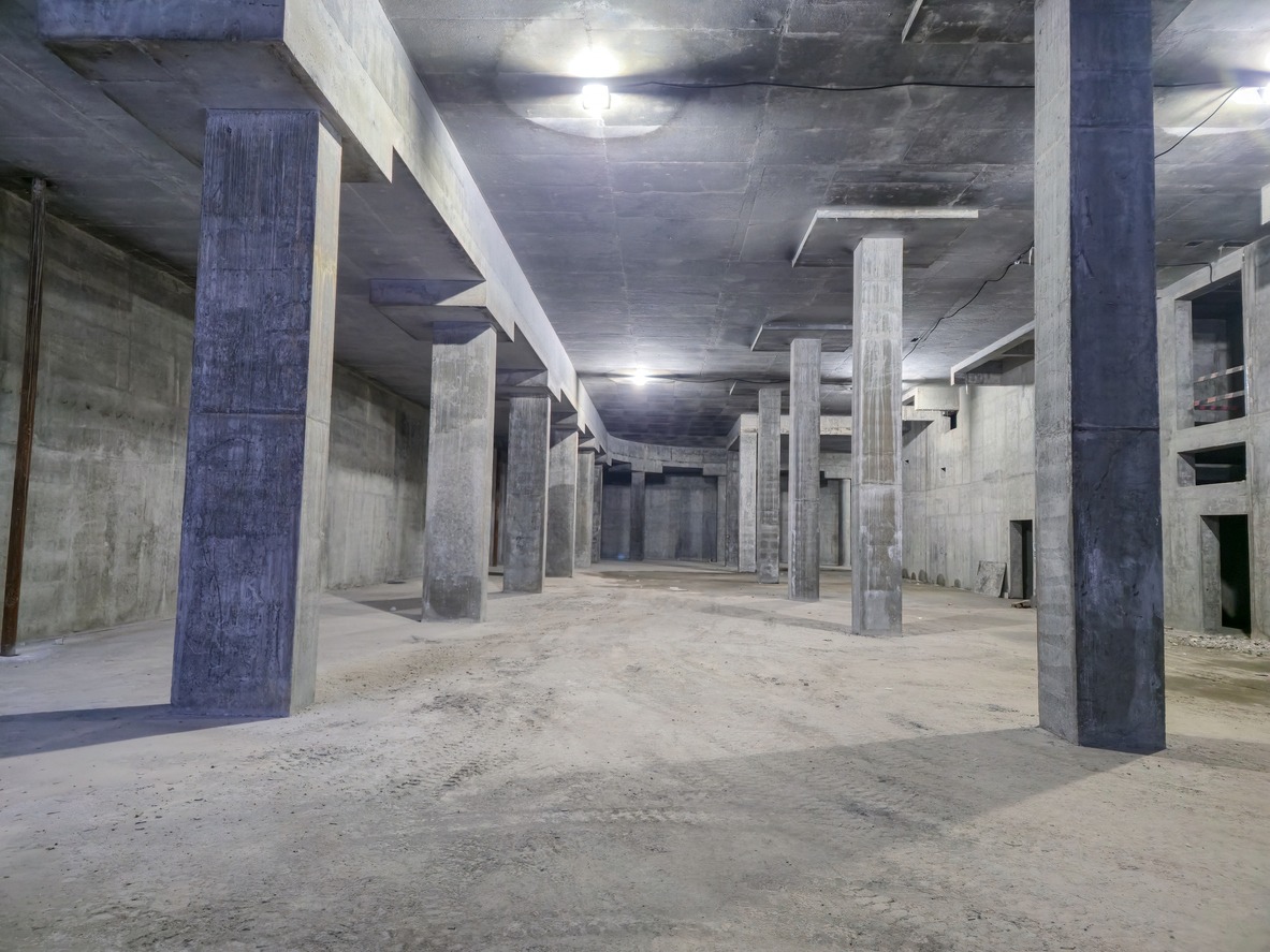 Empty concrete basement with support columns and lights